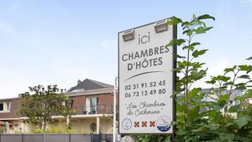 Une enseigne pour l’hôtel « Les Chambres de Catherine », avec les numéros de téléphone et le logo.