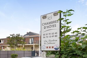 A sign for 'Les Chambres de Catherine' hotel with contact numbers and a logo.