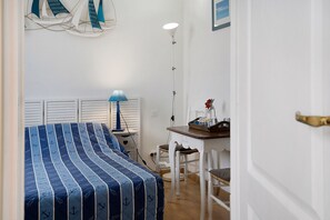 A bedroom with a bed, a nightstand, a lamp, a chair, and a small table with a vase. - Bed and Breakfast 'Chambre 3' with Shared Terrace, Shared Garden and Wi-Fi (Merville-Franceville-Plage)