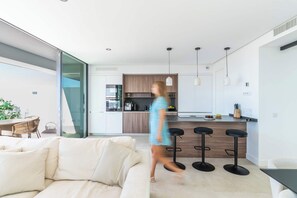 Een moderne keuken met een centraal eiland, barkrukken en hanglampen.