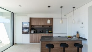 A modern kitchen with a central island, wooden cabinets, and pendant lighting. - Mirador Estepona Hills 15 | Pool & Private Jacuzzi (Estepona)