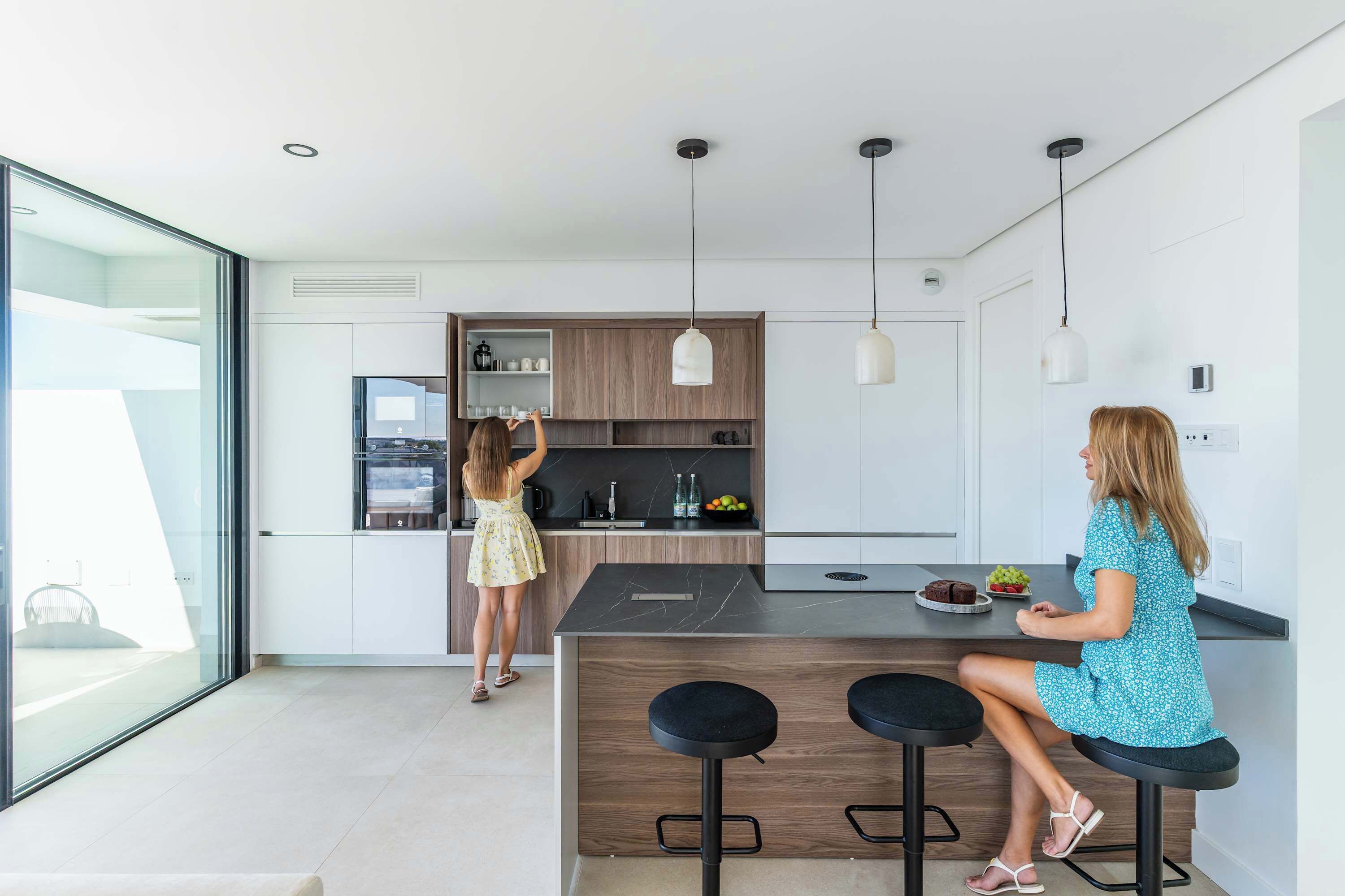 A modern kitchen with a central island, bar stools, and pendant lighting.