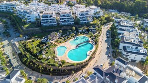 Ein Wohngebiet mit moderner Architektur, einem zentral gelegenen Schwimmbad und umgebender Grünfläche.