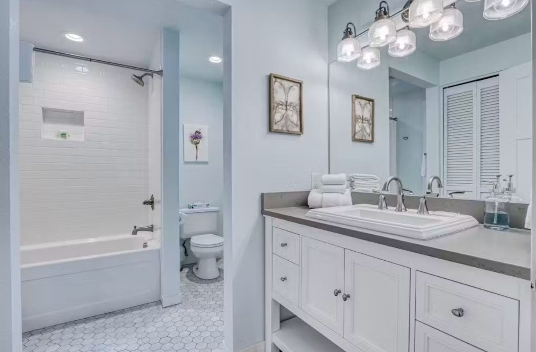A bathroom with a bathtub, toilet, vanity with a mirror, and a shower area.