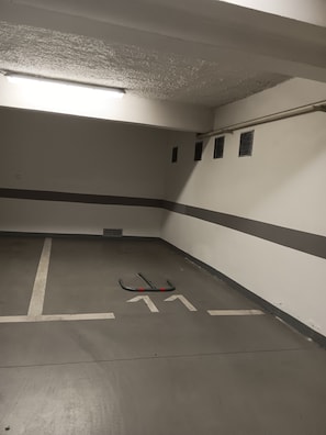 Eine Parkgarage mit weißen Wänden, grauen Bodenmarkierungen und einem Lüftungssystem.