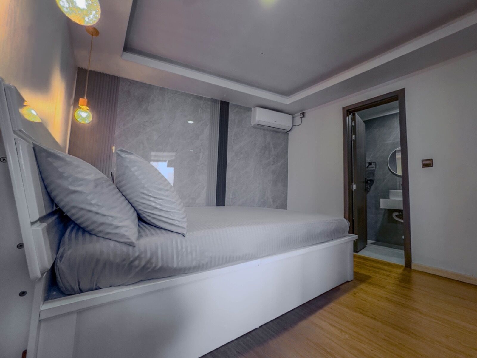 A modern bedroom with a built-in bed, a window, and a bathroom visible through an open door.