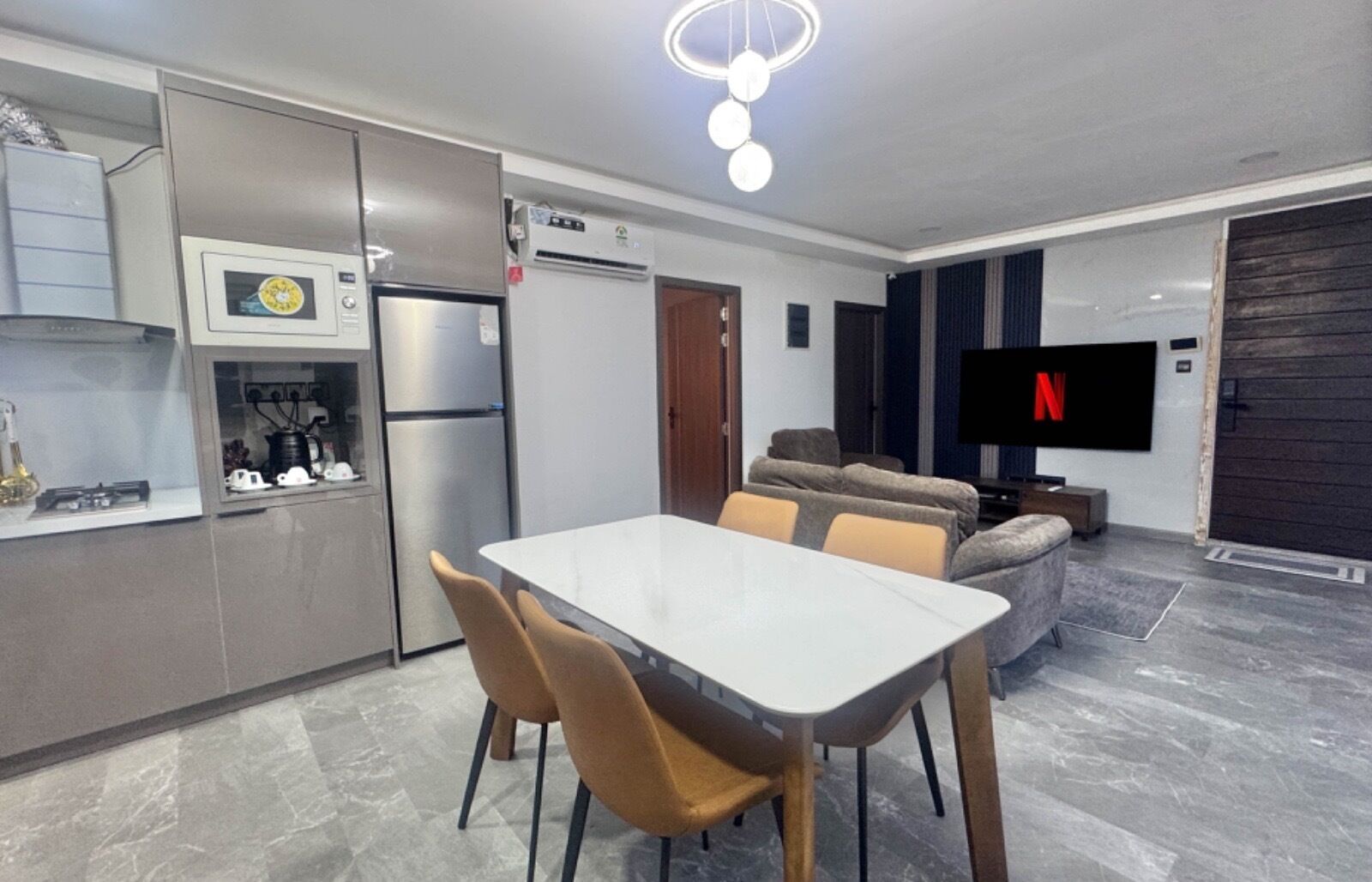 A modern kitchen with a dining area, a flat-screen TV, and a sofa.