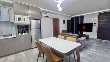 A modern kitchen with a dining area, a flat-screen TV, and a sofa.