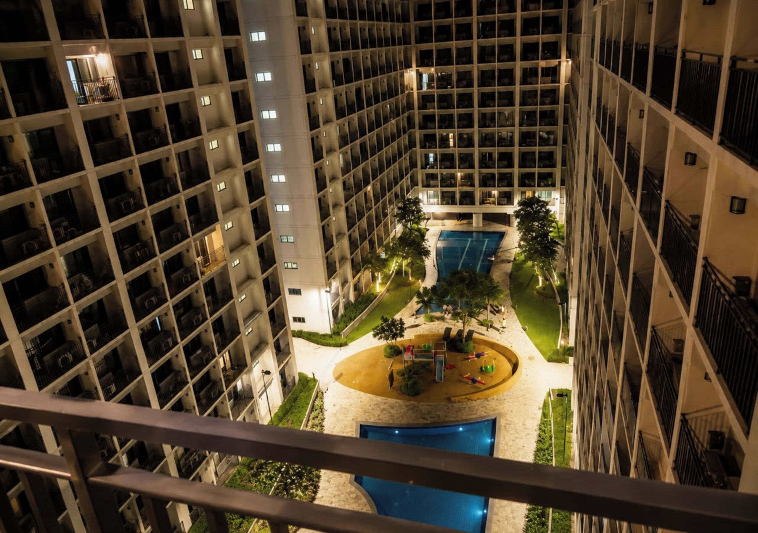 Un hotel moderno de muchas plantas, con un patio central que incluye una piscina y balcones.