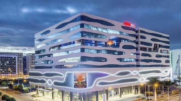 A multi-story building with a modern architectural design, featuring a prominent 'XOX' sign on the top.
