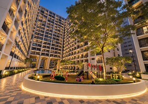 A multi-story hotel with a central courtyard featuring a playground, surrounded by high-rise buildings. - Grey & Wood 1BR w/ Pool View | Shore 2 Near MOA (Pasay City)