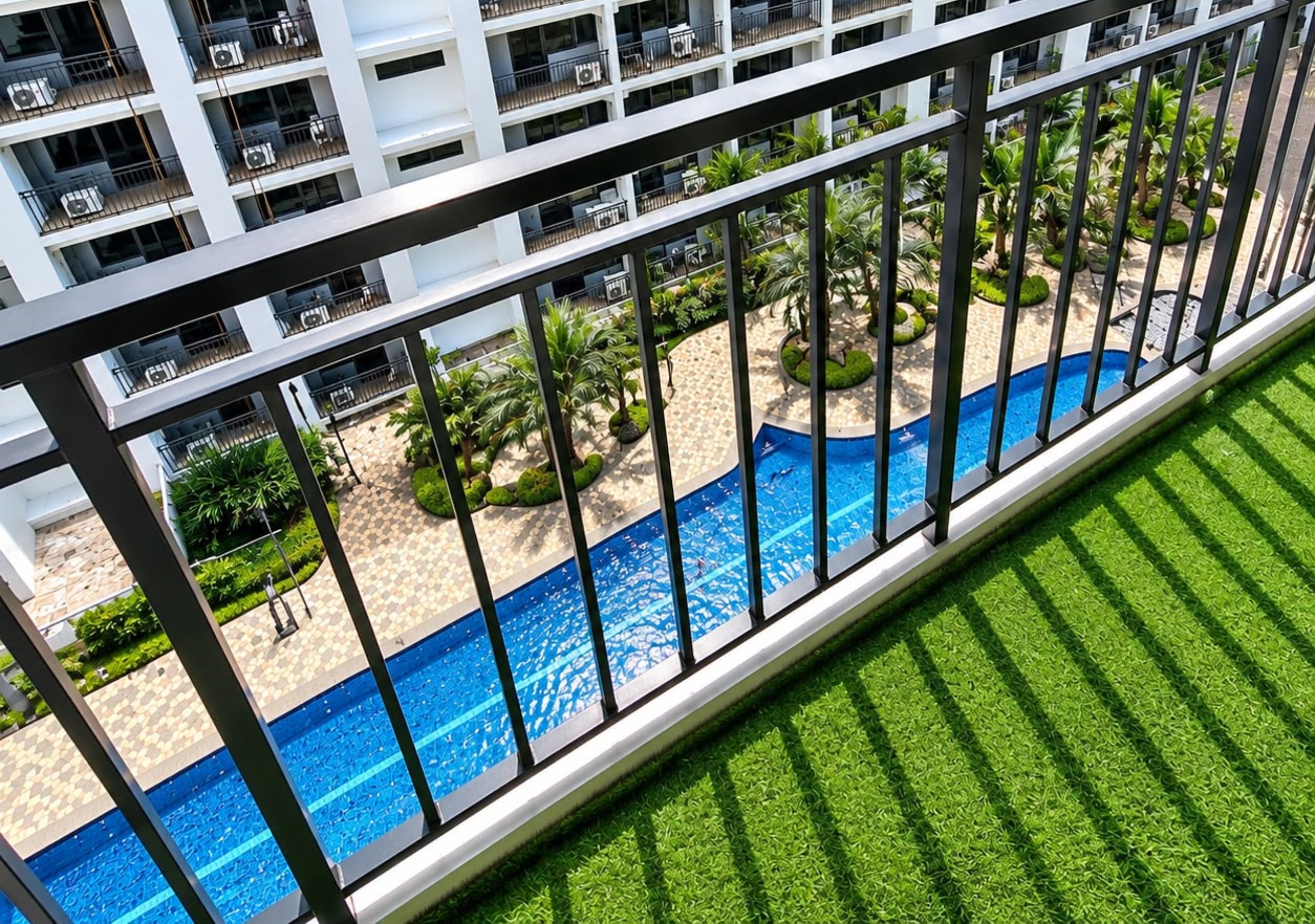 A pool area with a clear view of the surrounding landscape, including a beach and palm trees.