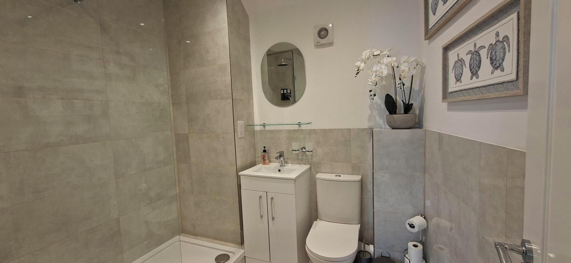 A bathroom with a shower, toilet, sink, and a mirror.