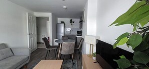 A compact living space with a dining area, kitchenette, and a grey sofa.