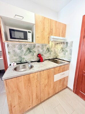 Cocina compacta con microondas, tostadora y pileta.