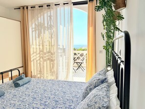 Un dormitorio con cama, vistas al exterior y una planta.