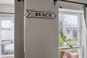 En vægmonteret skilt med ordet 'BEACH' og en piletavle.