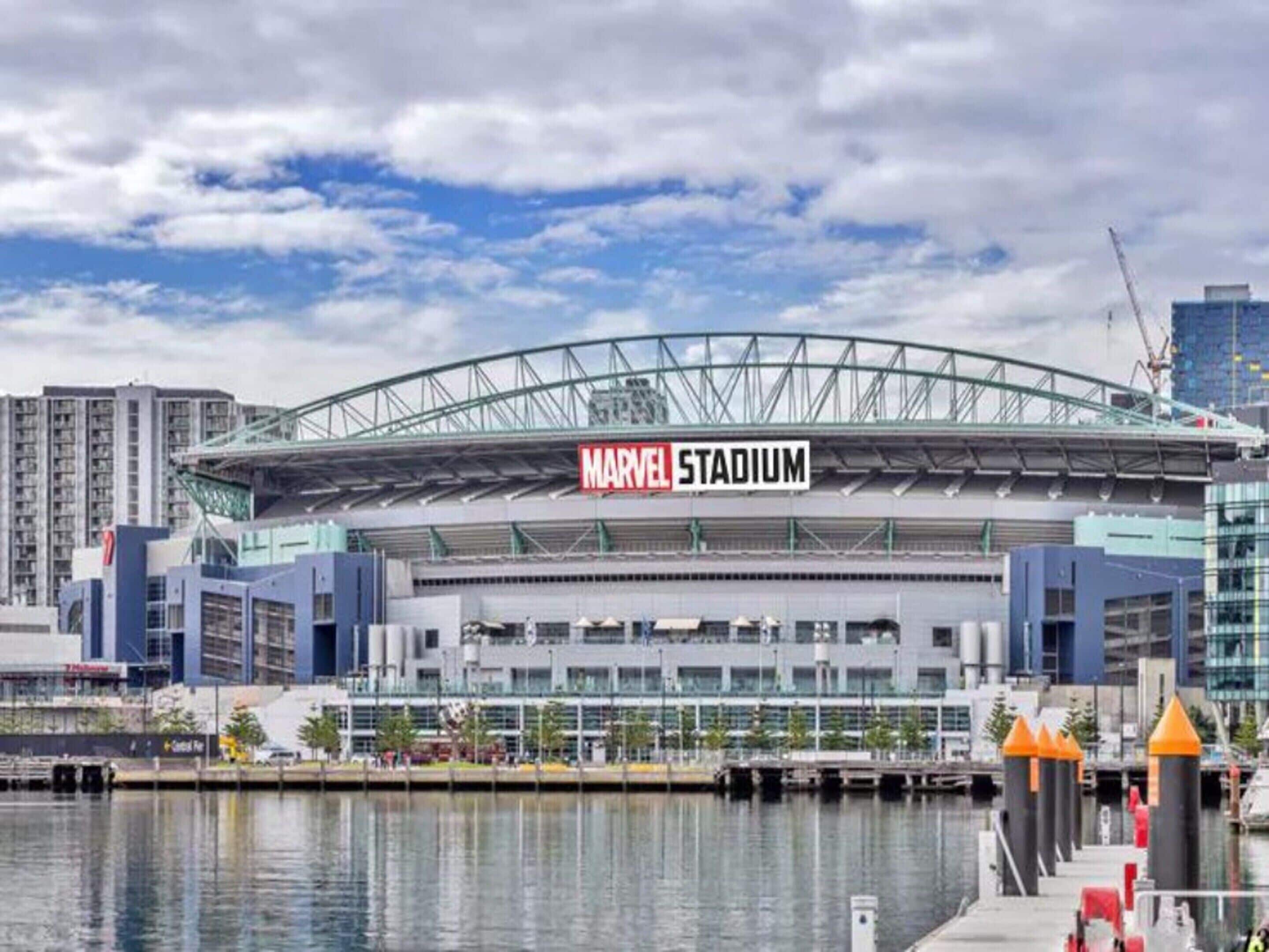En stadion med en stor skylt som visar texten ”MARVEL STADIUM”, och en strandpromenad i förgrunden.