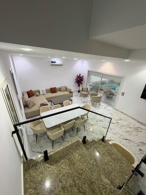 Ein modernes Interieur mit einer Sofagarnitur, einem Esstisch, Stühlen und einer Glaskonstruktion mit Blick.