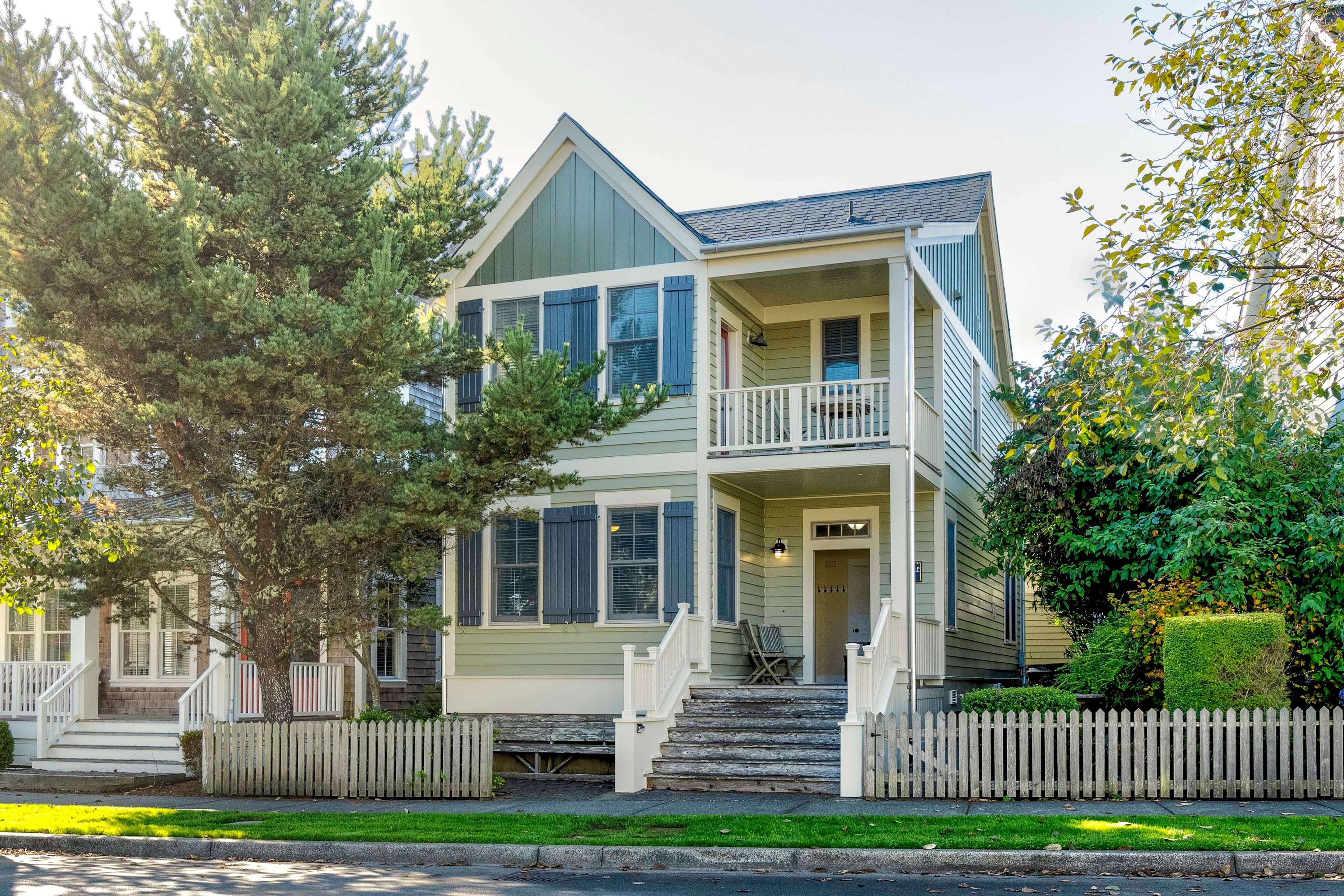 A two-story house with a front porch, a staircase, and a picket fence.