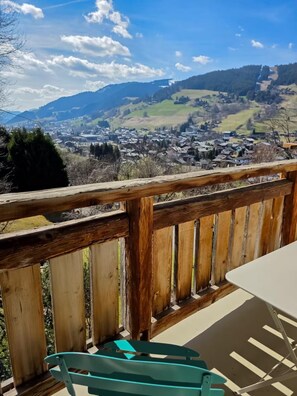 Una terraza de madera con vista a un pueblo y montañas a lo lejos.