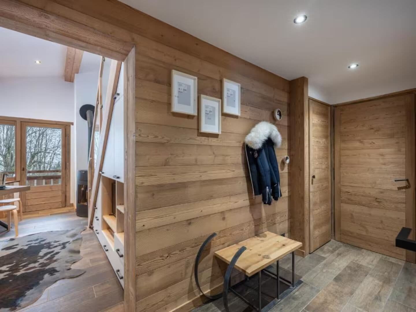 Arredamento in legno con una panca, un appendiabiti e quadri appesi al muro.