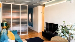 Ein modernes Wohnzimmer mit einer Couch, einem Flachbildfernseher und einer Pflanze.