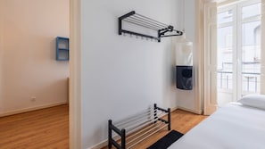 A hotel room with a bed, a wall-mounted drying rack, and a small blue shelf. - Arroios City Base | 2BR & Workspace by LovelyStay (Lisboa)
