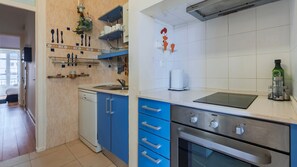 A modern kitchen with blue cabinets, a dishwasher, a stove, and a coffee maker. - Arroios City Base | 2BR & Workspace by LovelyStay (Lisboa)