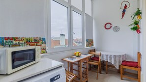 A compact kitchen with a microwave, a small refrigerator, and a dining area with a table and chairs. - Arroios City Base | 2BR & Workspace by LovelyStay (Lisboa)