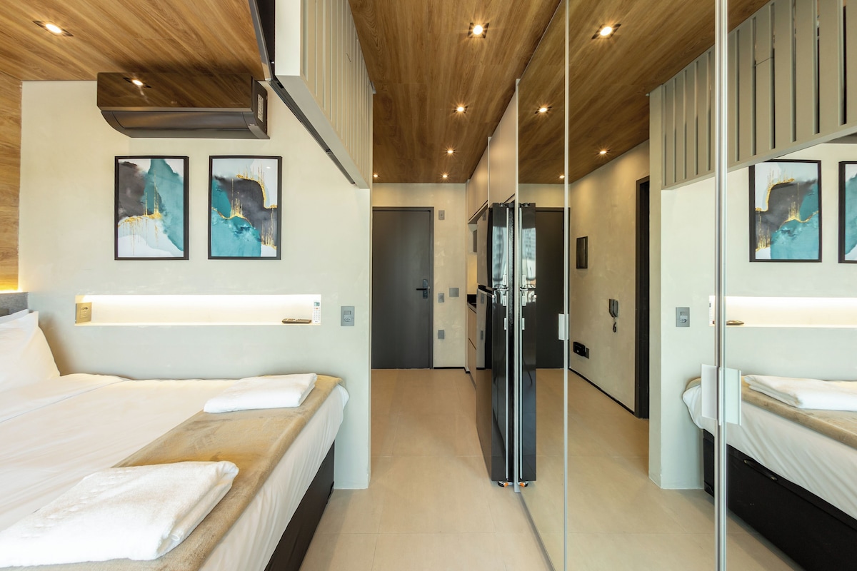 A hotel room with two beds, a large mirror, and artwork on the walls.