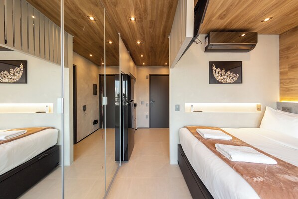 Une chambre d’hôtel moderne avec deux lits, un plafond en bois et des œuvres d’art accrochées aux murs.