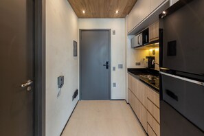 Une petite cuisine étroite avec une porte, un four à micro-ondes et un réfrigérateur.