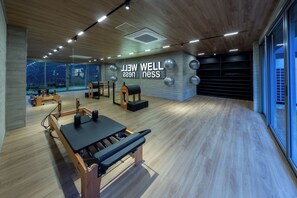 A modern gym with wooden floors, exercise equipment, and large windows. - Rodrigues by Bhomy (São Paulo)