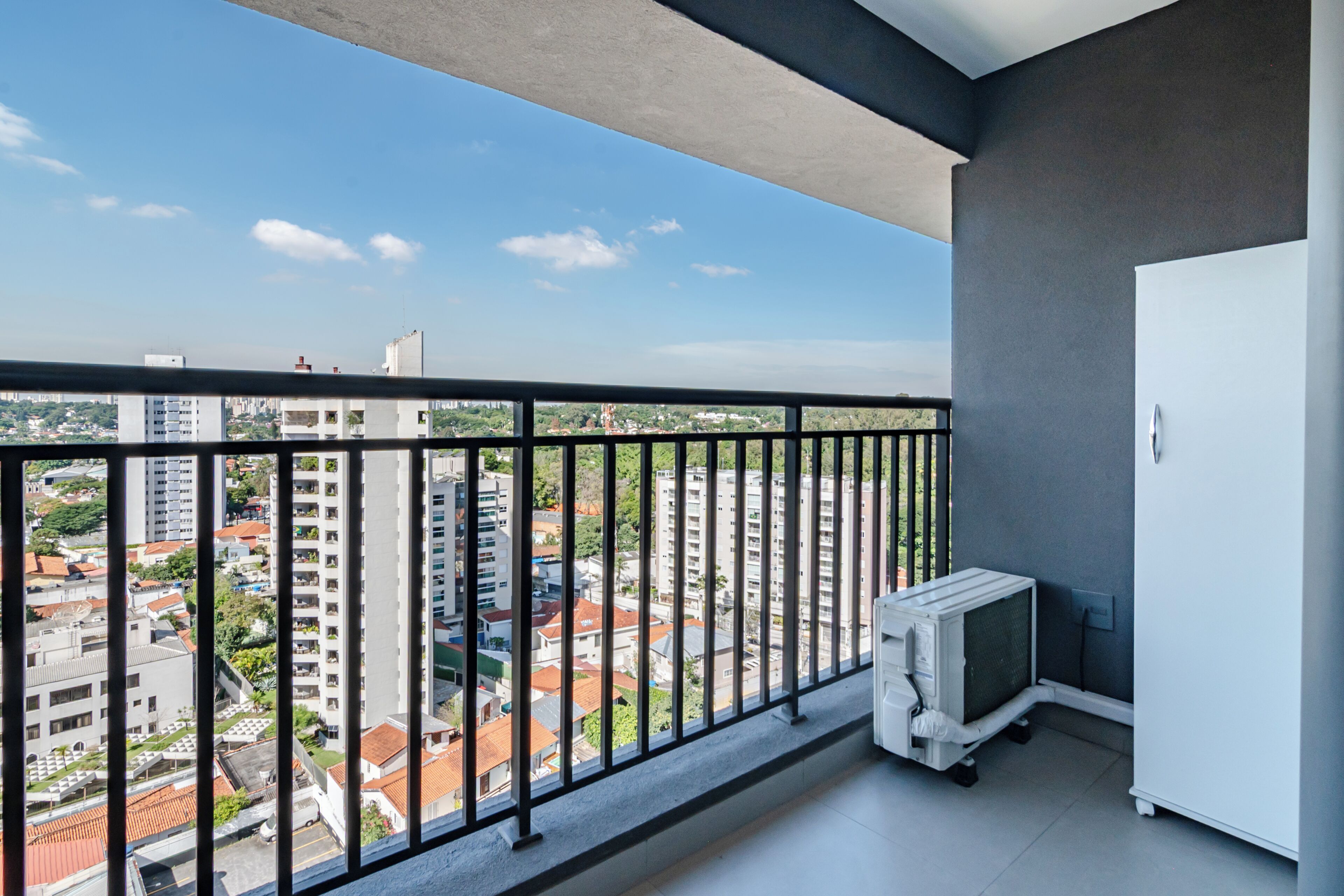 A balcony with a view of a cityscape, a white cabinet, and a white appliance.