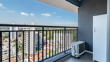 A balcony with a view of a cityscape, a white cabinet, and a white appliance.