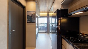 Eine moderne Küche mit einem schwarzen Herd, einer Glastür, die auf einen Balkon führt, und einem gerahmten Bild an der Wand.