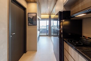 A modern kitchen with a black stove, a glass door leading to a balcony, and a framed picture on the wall. - Rodrigues by Bhomy (São Paulo)