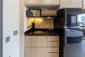 A compact kitchen with a built-in microwave, a coffee machine, and a stove. - Rodrigues by Bhomy (São Paulo)