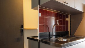 Eine moderne Küche mit Einbauherd, Spüle und Schrank mit roten Fliesenrückwand.