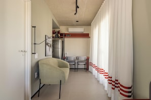 A narrow hallway with a chair, a table, and a refrigerator. - Rodrigues by Bhomy (São Paulo)