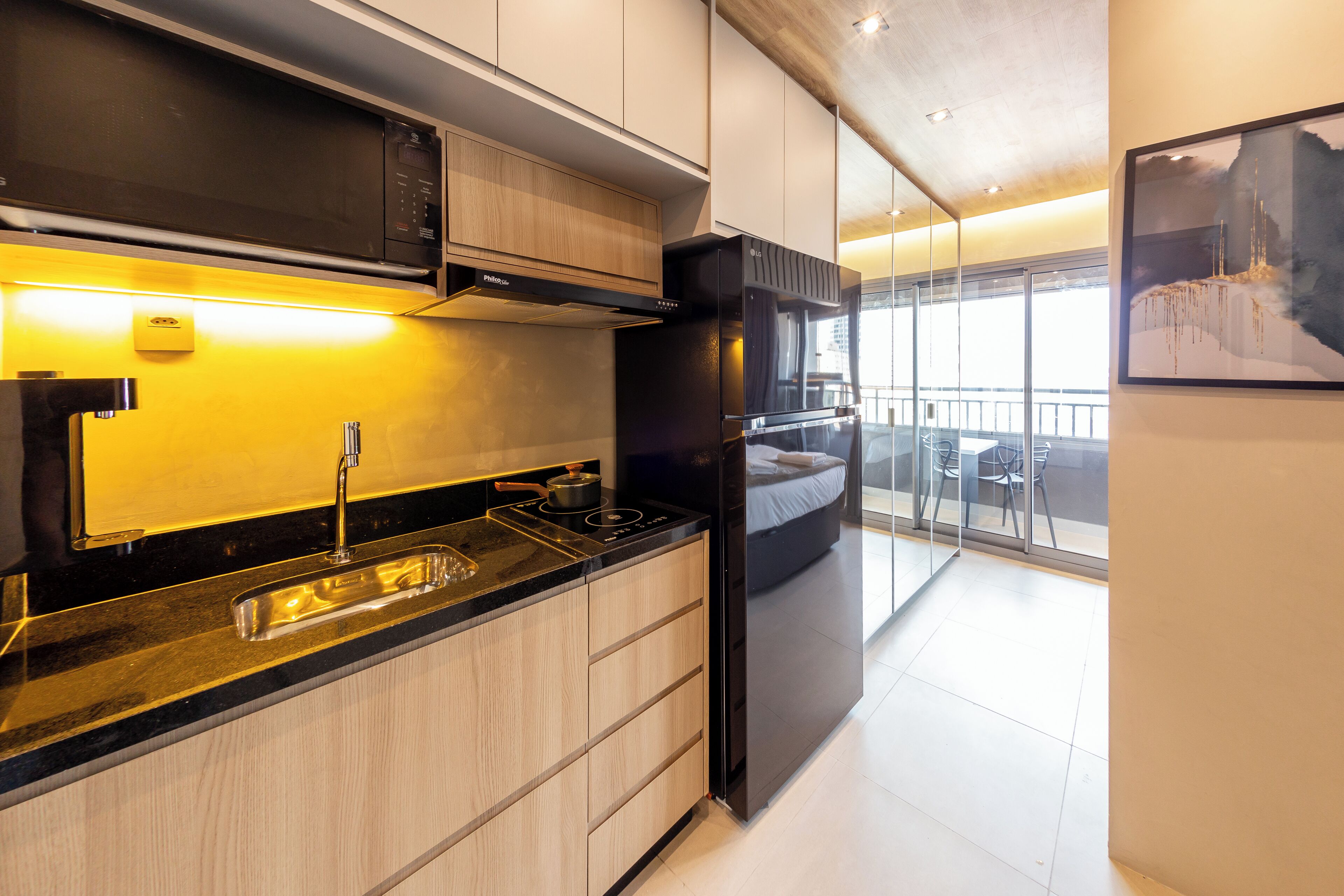 A modern kitchen with a built-in oven, a sink, and a dining area with a view.