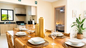 A dining area with a wooden table set for four, surrounded by woven chairs. - 3-Bedroom Villa Near the Beaches / Pool / Gym / Near Downtown Punta Cana (Punta Cana)