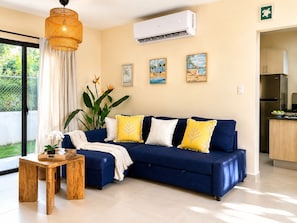 A modern living room with a blue sofa, yellow cushions, a wooden coffee table, and a hanging light fixture. - 3-Bedroom Villa Near the Beaches / Pool / Gym / Near Downtown Punta Cana (Punta Cana)