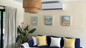 A living room with a blue sofa, a wooden coffee table, and a hanging rattan light fixture. - 3-Bedroom Villa Near the Beaches / Pool / Gym / Near Downtown Punta Cana (Punta Cana)