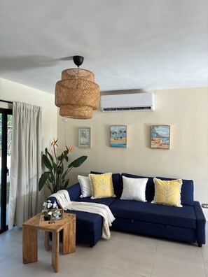 A living room with a blue sofa, a wooden coffee table, and a hanging rattan light fixture. - 3-Bedroom Villa Near the Beaches / Pool / Gym / Near Downtown Punta Cana (Punta Cana)