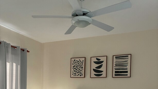 A bedroom with a bed, a desk, a chair, a nightstand, a ceiling fan, and wall art. - 3-Bedroom Villa Near the Beaches / Pool / Gym / Near Downtown Punta Cana (Punta Cana)