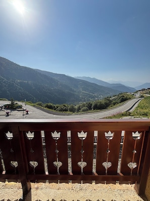 A balcony with a view of a winding road and distant mountains.