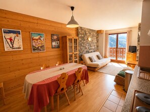 A cozy room with a dining table, a sofa, and a stone wall.
