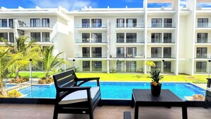 A modern hotel with a pool area, featuring a bench and a table with a potted plant. - Walk 2 Fun, Beaches, Dining, Shopping, Nightlife (Punta Cana)